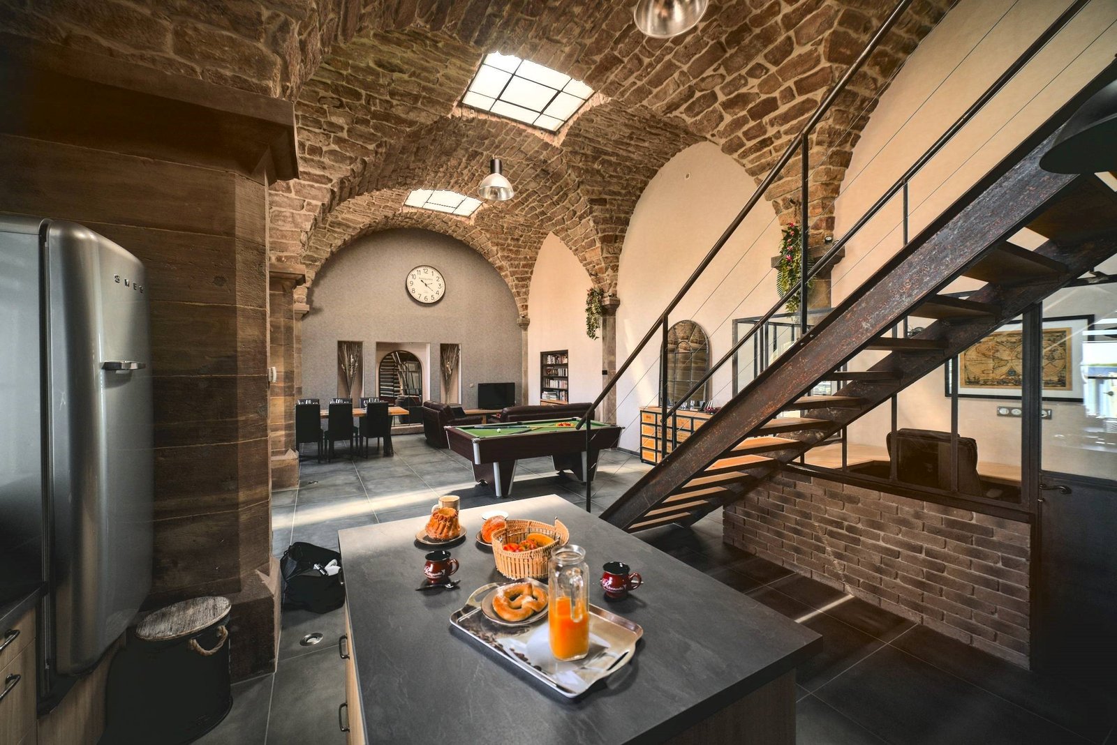 Vue intérieure de La Chapelle Industrielle avec voûtes en pierre, billard, escalier et cuisine à Issenheim